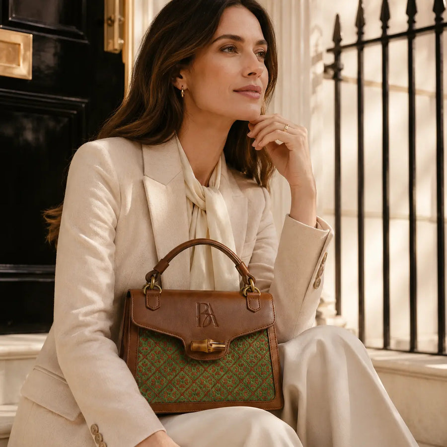 Model wearing Bamboura Heritage Arc bamboo leather handbag in refined neutral outfit styling