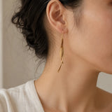 Close-up of Bamboura Wind Chimes lightweight bamboo earrings worn on ear