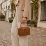 Model carrying the Regent Weave handwoven bamboo box bag with bamboo handle in an elegant street style look