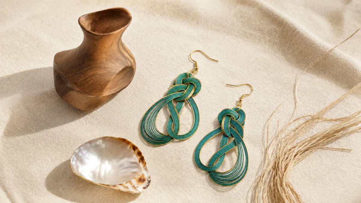Handwoven bamboo earrings with carved wood, polished shell and natural raffia arranged on warm ivory linen
